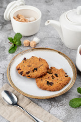 American chocolate chip cookies on rustic plate with sugar, mint and teapot on background