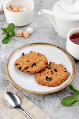American chocolate chip cookies on rustic plate with sugar, mint and teapot on background