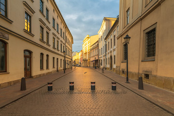 Oświetlona słońce zabytkowa ulica w centrum miasta. Z przodu słupki ograniczające wjazd