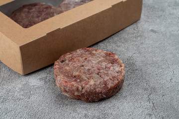 Frozen ready-to-cook beef patties next to cardboard box