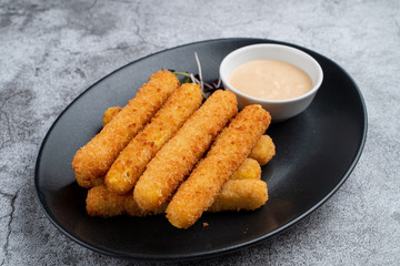 Stack of deep fried mozzarella cheese sticks with hot melted cheese inside, served with sauce on...