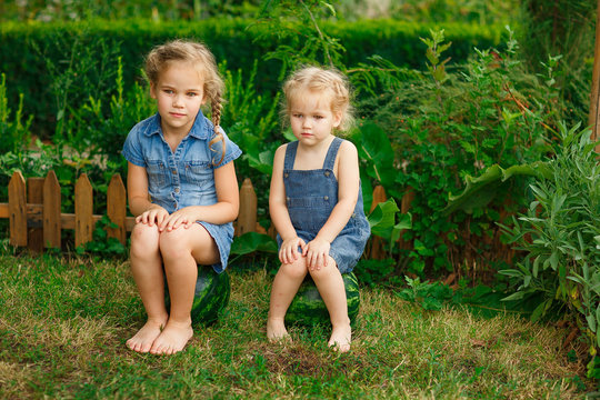 Little girls with bare legs sitting on watermelon