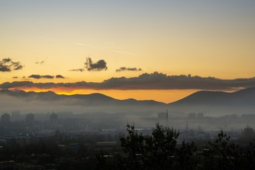 Sunrise and sunset, beautiful clouds over the meadow, hills and buildings in the town. Slovakia