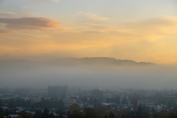 Fototapeta premium Sunrise and sunset, beautiful clouds over the meadow, hills and buildings in the town. Slovakia