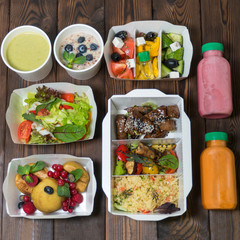 Dietary food in containers with you. Food delivery. Breakfast, lunch and dinner. On a wooden background. The food assortment is calculated in calories. Take with you. Healthy diet.