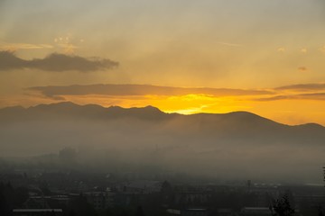 Sunrise and sunset, beautiful clouds over the meadow, hills and buildings in the town. Slovakia