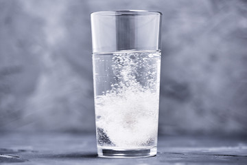 Effervescent vitamin C tablet bubbles in glass of water
