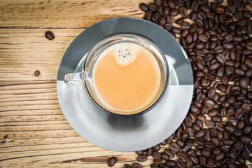 Cup of coffee and coffee beans on wooden  background.