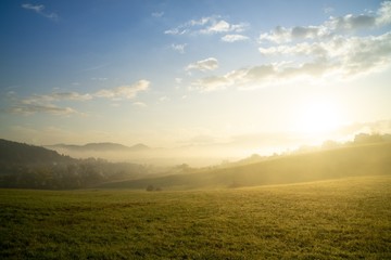 Sunrise and sunset, beautiful clouds over the meadow, hills and buildings in the town. Slovakia