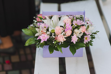 Fresh flowers close-up in a wooden basket for congratulations. Wedding gift of flowers: roses, chrysanthemums, violets, lilies. Photography, concept.
