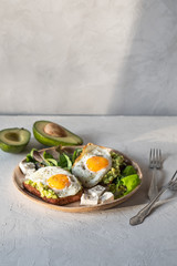 Healthy breakfast- sandwich prepared with guacamole, pepper and fried eggs with feta cheese and avocado on grey background