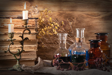 Old magic book, magical potions and dried herbs on witch doctor table background. Witchcraft concept.