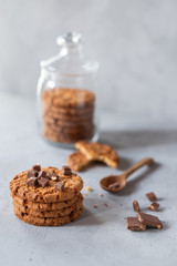 A stack of freshly baked cookies in a glass jar with a glass of milk on a gray background. close-up. quick snack