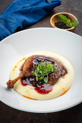 Cooked Duck legs with mashed potatoes with lingonberry sauce and herbs, close up