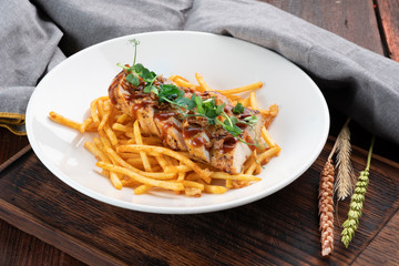 Chicken fillet cut into pieces with French fries on a white plate, a dish for lunch