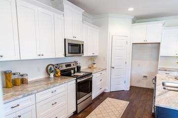 New construction modern kitchen with white cabinets and hardwood floors - obrazy, fototapety, plakaty