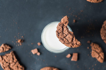 traditional freshly baked chocolate cookies, glass of milk on a black background close-up. quick snack