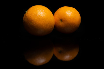 Arrangement with fruits on a shiny black surface with black background.
