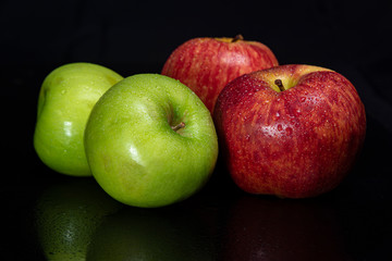 Arrangement with fruits on a shiny black surface with black background.