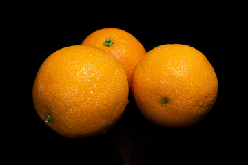 Arrangement with fruits on a shiny black surface with black background.