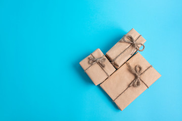 Gifts in eco-friendly packaging made of craft, recycled paper on a light, sky blue background.