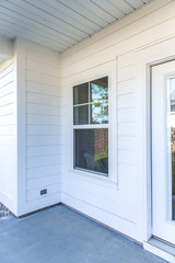 Exterior of a white siding house with a porch nook and a window