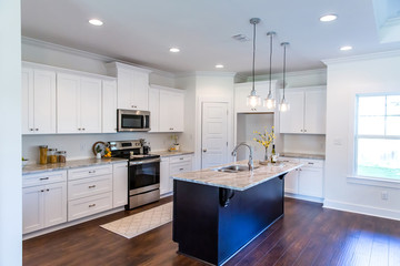 New construction modern kitchen with white cabinets and hardwood floors