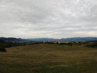 Sunrise and sunset, beautiful clouds over the meadow, hills and buildings in the town. Slovakia