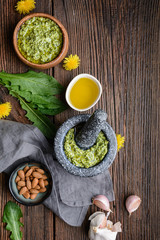 Healthy dandelion pesto with almonds, garlic, olive oil and Parmesan cheese in a stone mortar