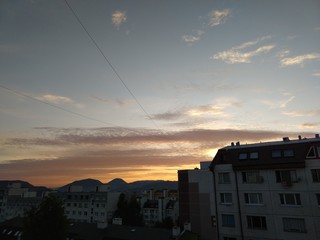 Sunrise and sunset, beautiful clouds over the meadow, hills and buildings in the town. Slovakia