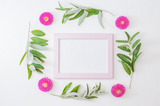 Flat lay mockup with a pink frame flowers and green leaves on a white background