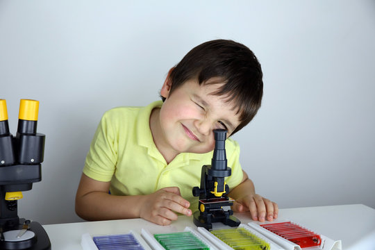 ni&ntilde;o con microscopio y y lupa binocular mirando muestras biol&oacute;gicas preparadas en portaobjetos