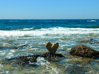 Stone in the shape of a heart on the sea coast. Beautiful summer landscape.