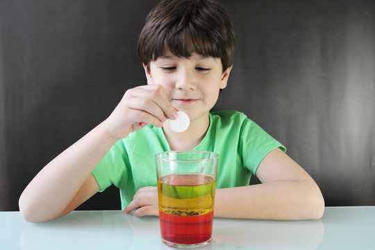 Ni&ntilde;o realizando un experimento casero durante la cuarentena por coronavirus, es una l&aacute;mpara de lava con agua, aceite, colorante, pastilla efervescente. Paso 4 echar pastilla efervescente.
