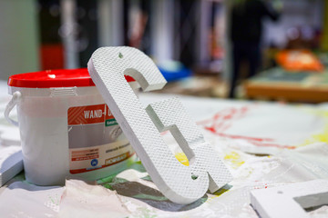 Der Buchstabe G liegt ausgefr&auml;st angekippt an einem Farbeimer.