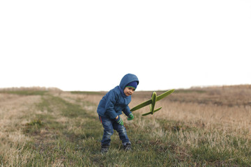 Naklejka na ściany i meble Boy playing with toy glider in field on spring day