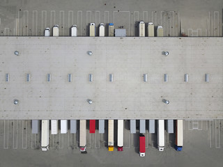 Aerial view of goods warehouse. Logistics center in industrial city zone from above. Aerial view of trucks loading at logistic center