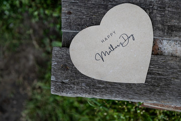 Happy Mother's Day written on a paper card on a rustic old bench