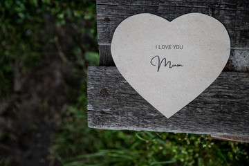 I love You Mum written on a paper card on a rustic old bench