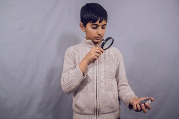 boy looking through a magnifying glass at a compass
