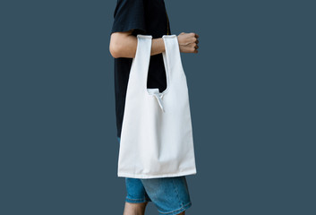 Man is holding bag canvas fabric for mockup blank template on gray background.