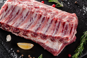 Raw meat. Raw pork ribs from the back with meat on a black background. background image, copy space text
