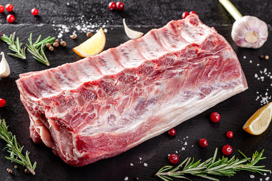Raw meat. Raw pork ribs from the back with meat on a black background. background image, copy space text