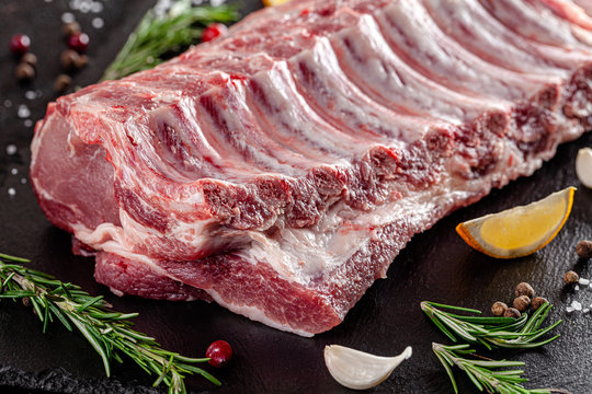 Raw meat. Raw pork ribs from the back with meat on a black background. background image, copy space text