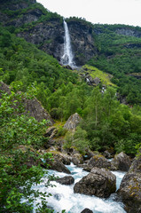 View of the beautiful big waterfall Rjoandefossen  with green summer mountain views near the famous Flam village in Norway