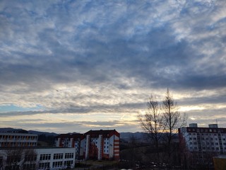 Fototapeta premium Sunrise and sunset, beautiful clouds over the meadow, hills and buildings in the town. Slovakia