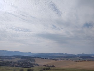 Obraz premium Sunrise and sunset, beautiful clouds over the meadow, hills and buildings in the town. Slovakia