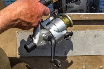 Old fishing reel in the hand of a fisherman. copy space. close up