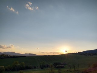 Fototapeta premium Sunrise and sunset, beautiful clouds over the meadow, hills and buildings in the town. Slovakia