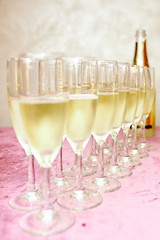 Crystal, clean wine glasses with chilled expensive champagne stand on a table with a pink tablecloth 